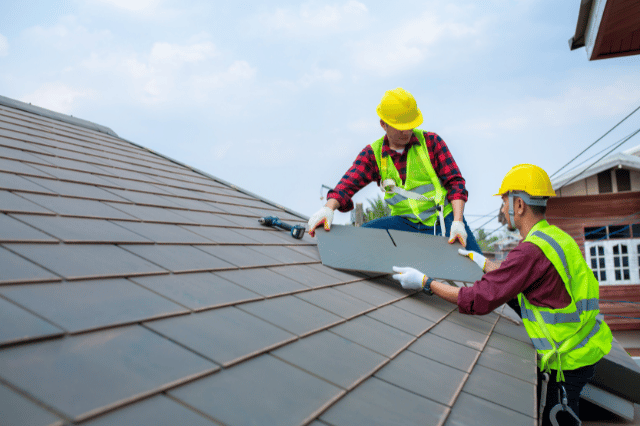 Two builders replacing roof tiles