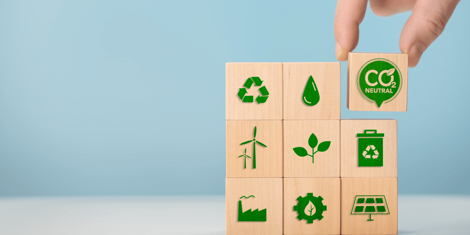 Fingers picking up wooden cube with a Co2 symbol in green