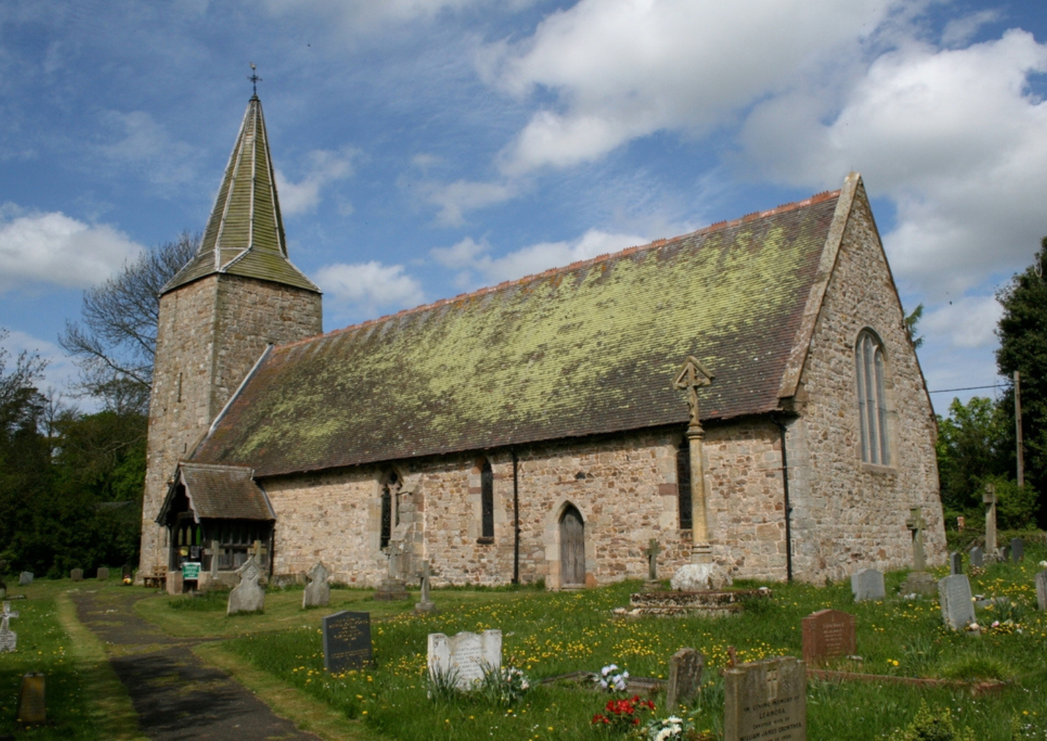 St John the Batist Church in Nash South Shropshire, blue sky and clouds, church and churchyard with flowers