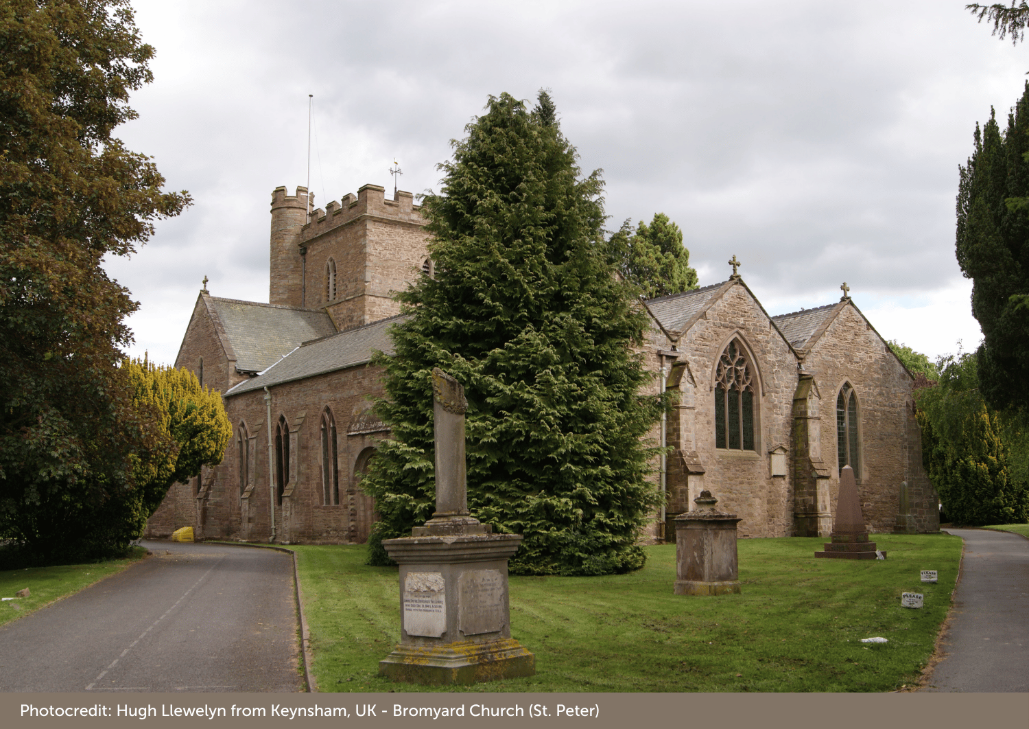 Picture of a church looking up the church path towards the building. Blue sky and trees