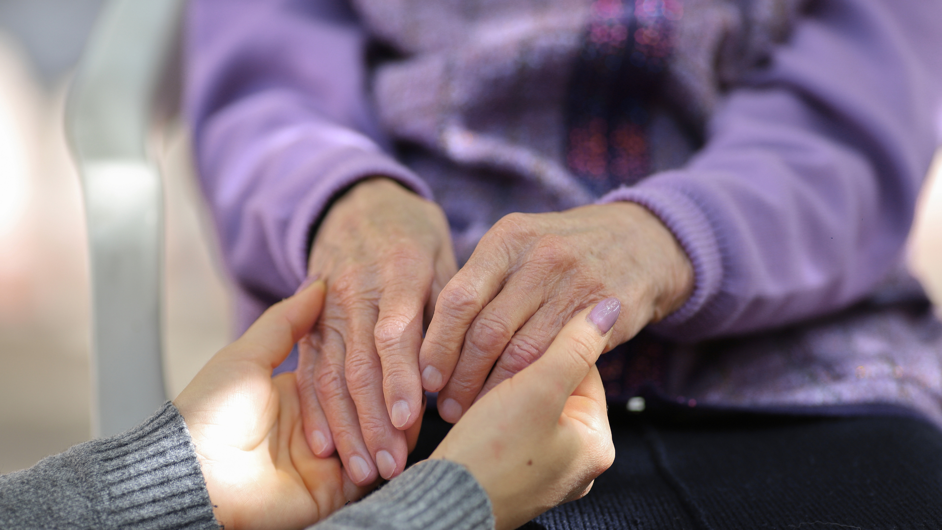 Volunteer holding elderly persons hands