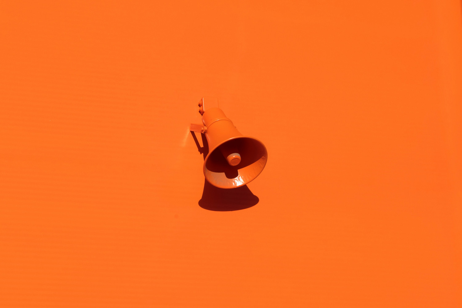 Image of an orange megaphone on an orange painted wall