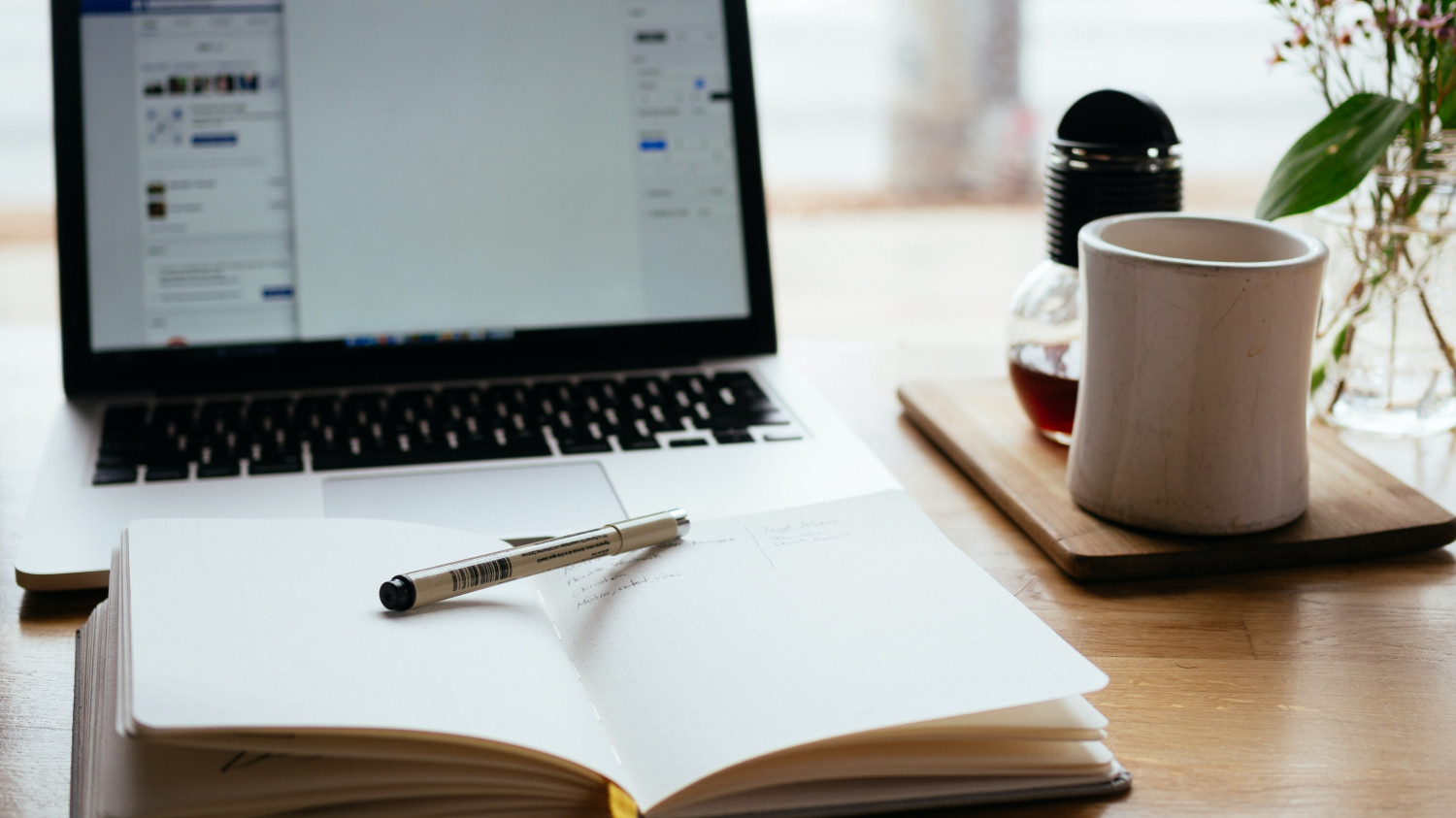 Image of an open notepad and laptop on a desk