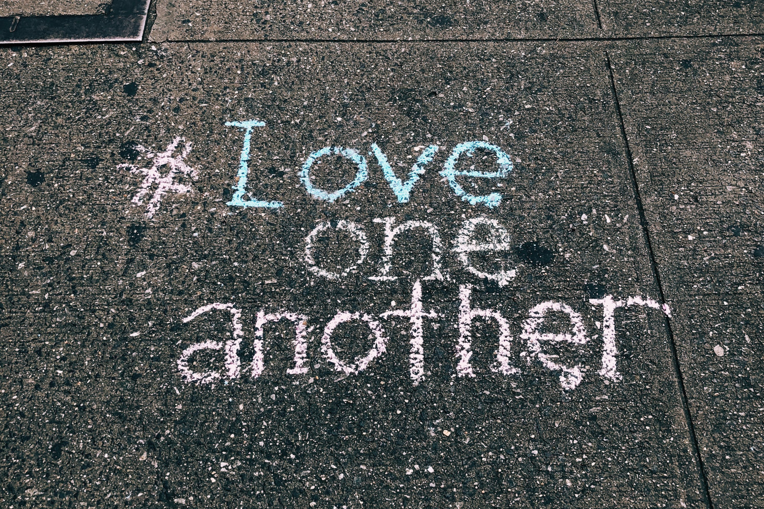 Image of pavement with 'Love one another' written in chalk