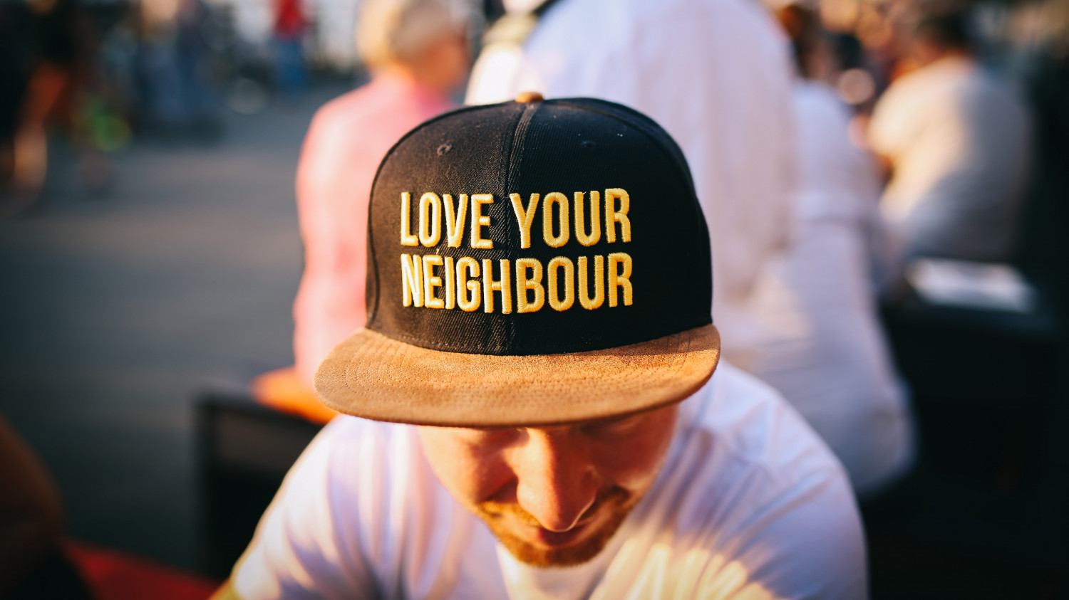 Image of a man wearing a baseball reading "Love you neighbour"